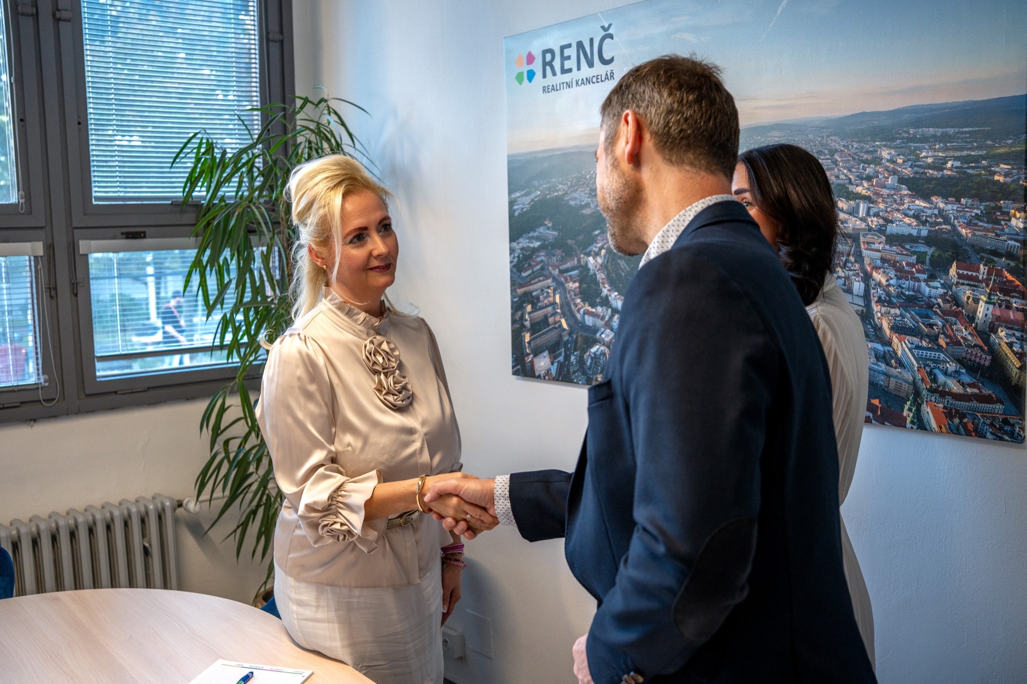 Makléřka RENČ podává klientovi ruku v kanceláři na Kounicově
